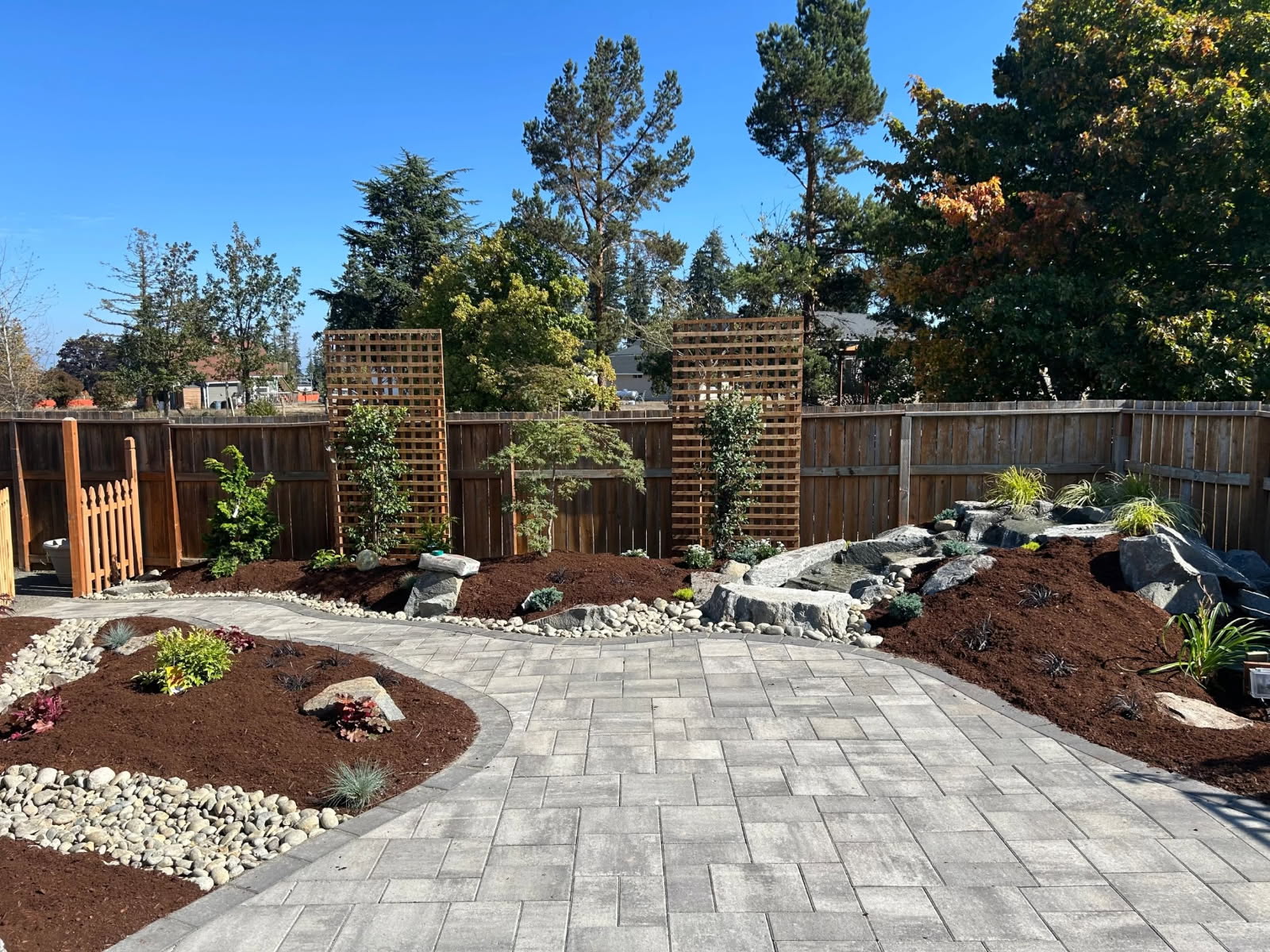 Complete backyard landscape by Sage Landscape & Design — paver patio, planted beds and boulder water feature